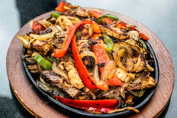 Black skillet of fajitas with steak, chicken, onions, and peppers | 1958 Piedmont Rd NE, Atlanta, GA 30324