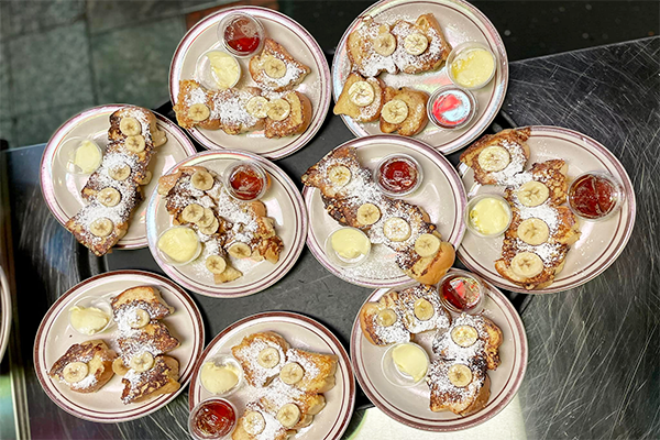 Several plates of french toast with powdered sugar and sliced bananas | 1812 Peachtree Rd NE, Atlanta, GA 30309