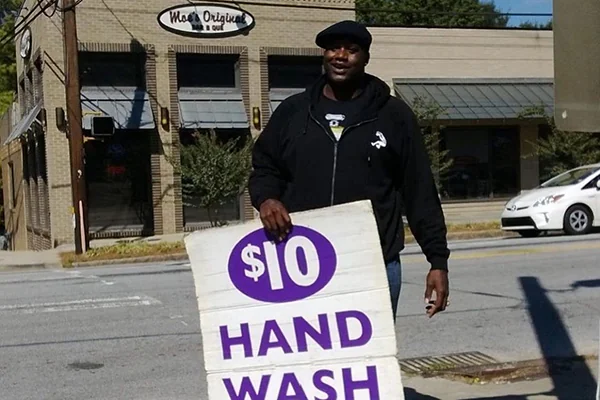 NBA legend and Auto Spa Bistro board member Shaquille O'Neal holds a sign for a $10 Hand Wash outside the Auto Spa Bistro in Atlanta, GA. | 348 14th St NW, Atlanta, GA 30318