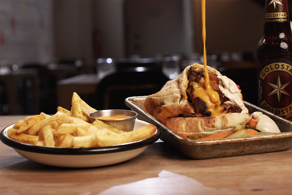 A pita being drizzled with sauce next to a plate of fries from Rinna in Old Fourth Ward.